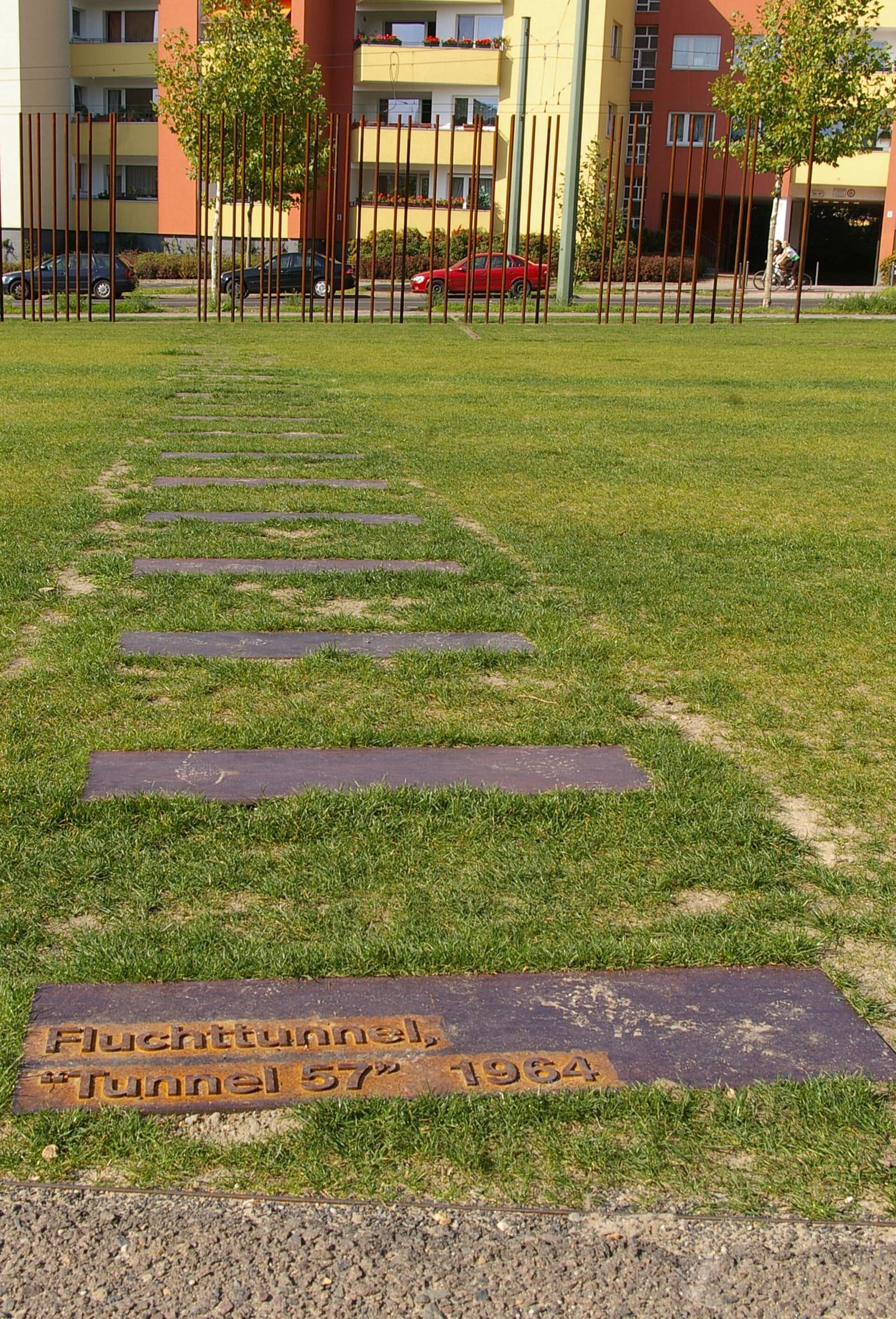 Line of rusted steel plates set into a lawn, tracing the course of a tunnel