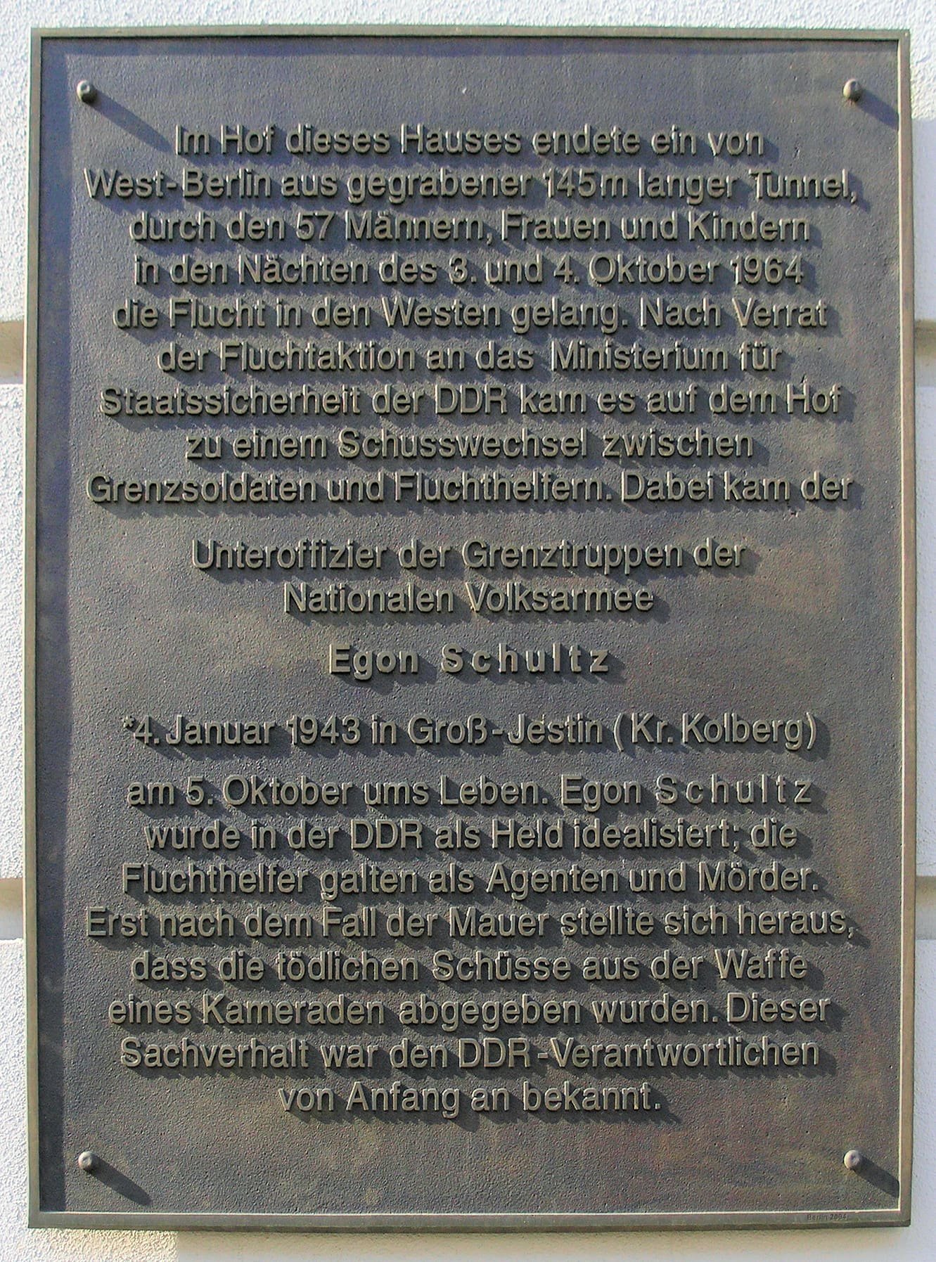 A plaque on a wall with text about Tunnel 57 and Egon Schultz.