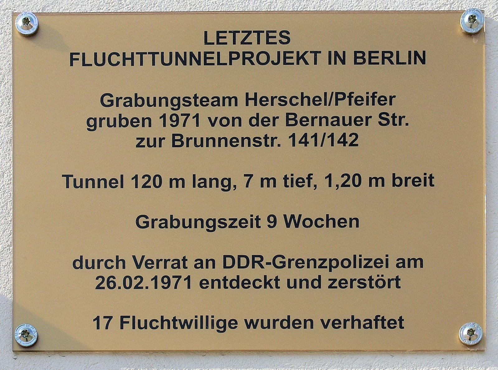 A brass-coloured plaque headed 'Letztes Fluchttunnelprojekt in Berlin' giving the tunnel's length, depth and width, the nine weeks of digging, the discovery date and the 17 arrests.