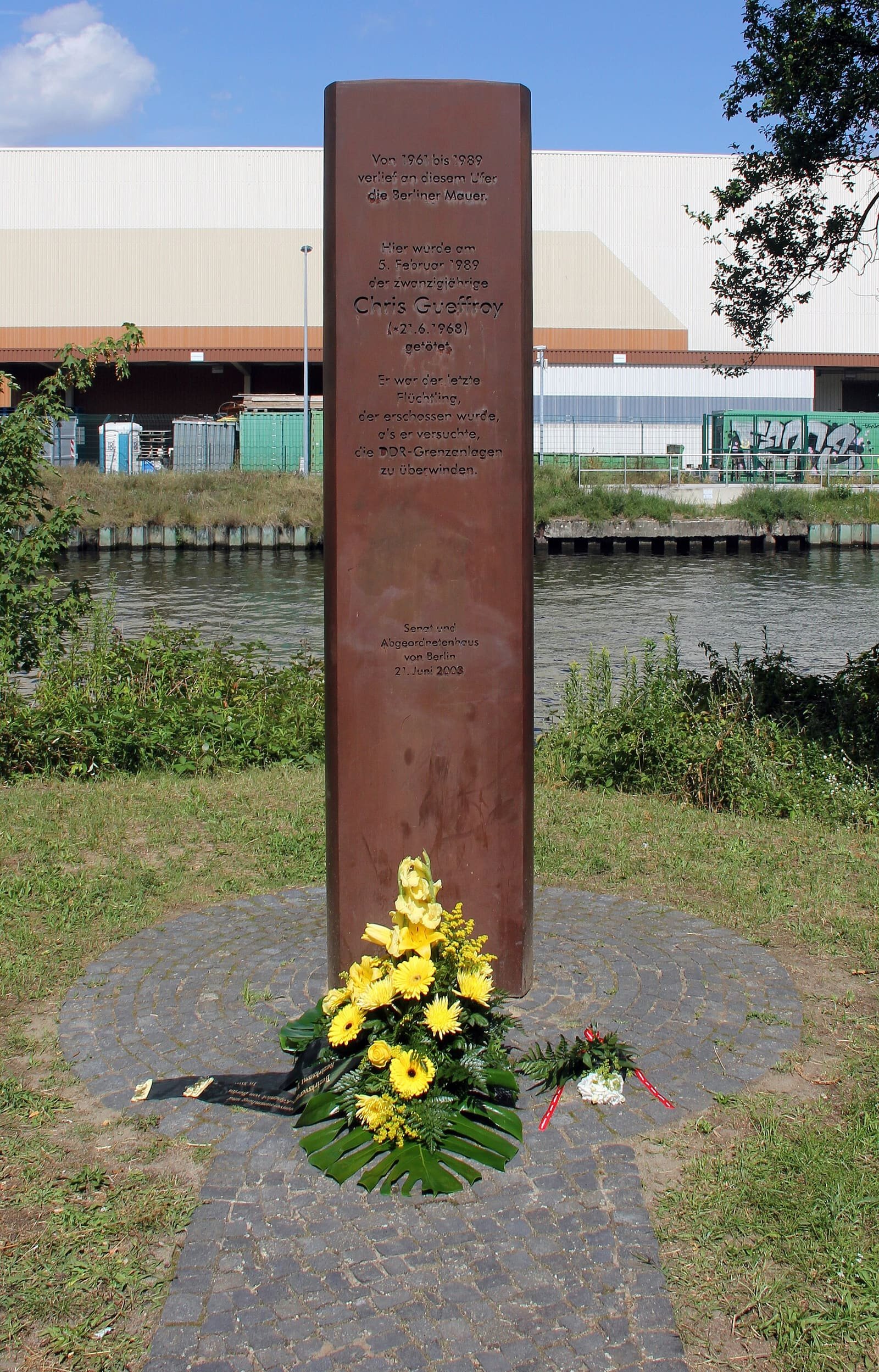 Tall slender steel steles on a grassy canal bank