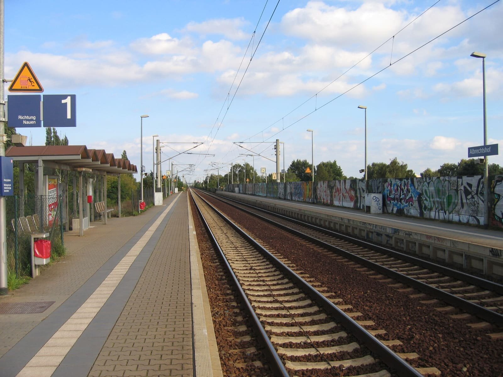 A suburban railway station with platform and tracks.
