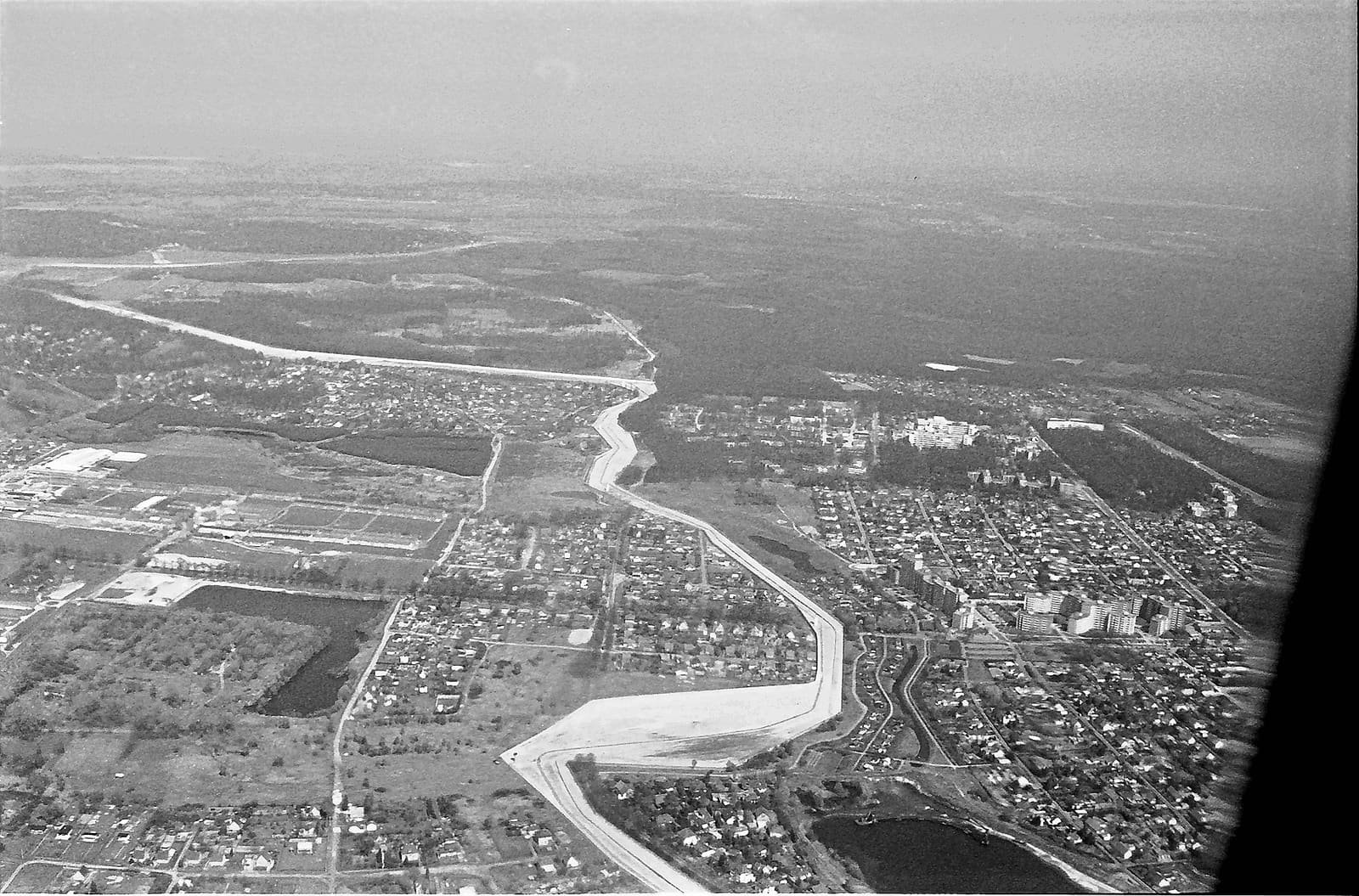 Aerial photograph of the border strip cutting across fields and a road between a town and housing estates