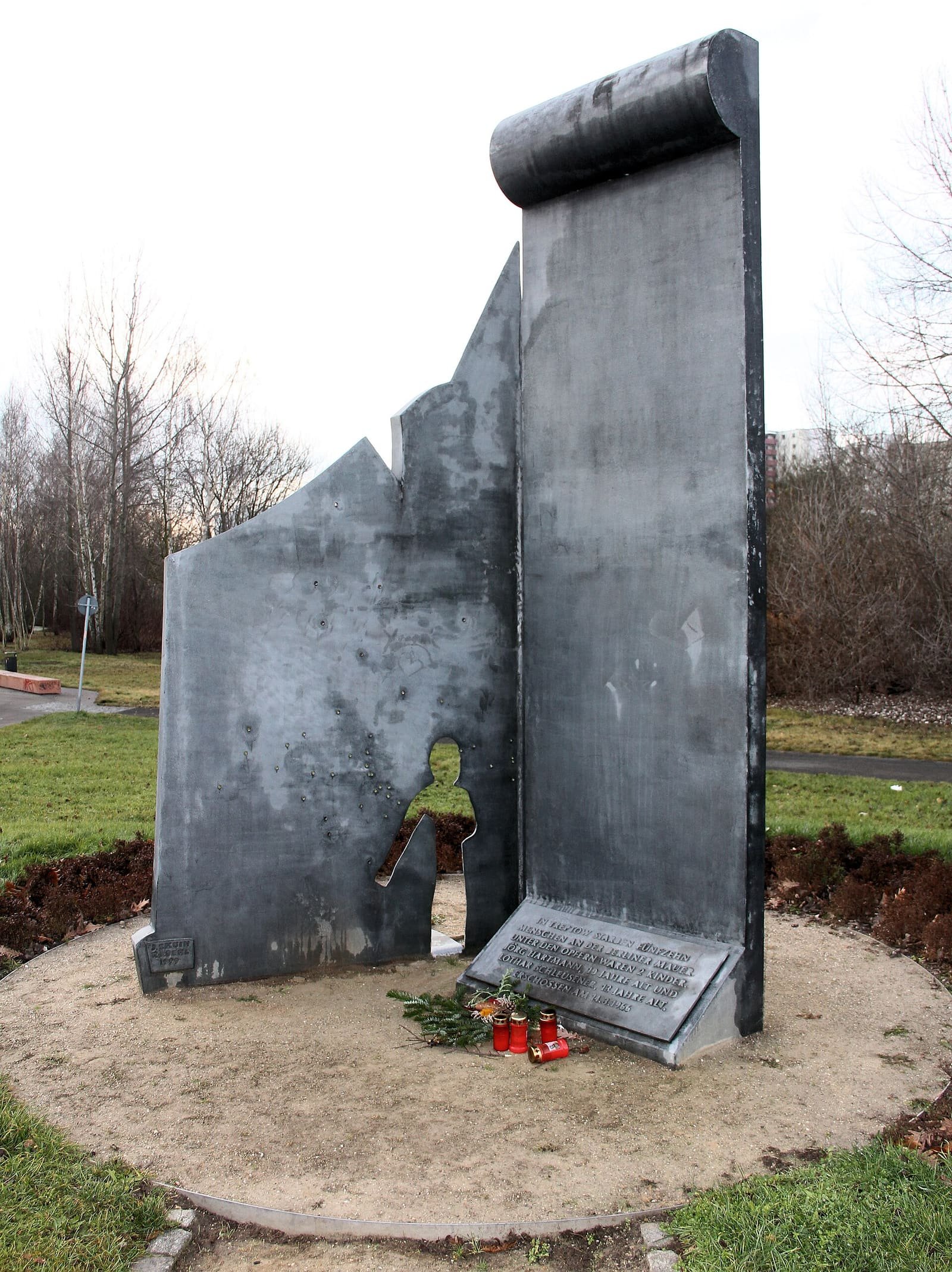 An outdoor memorial sculpture standing in a green space beside a path