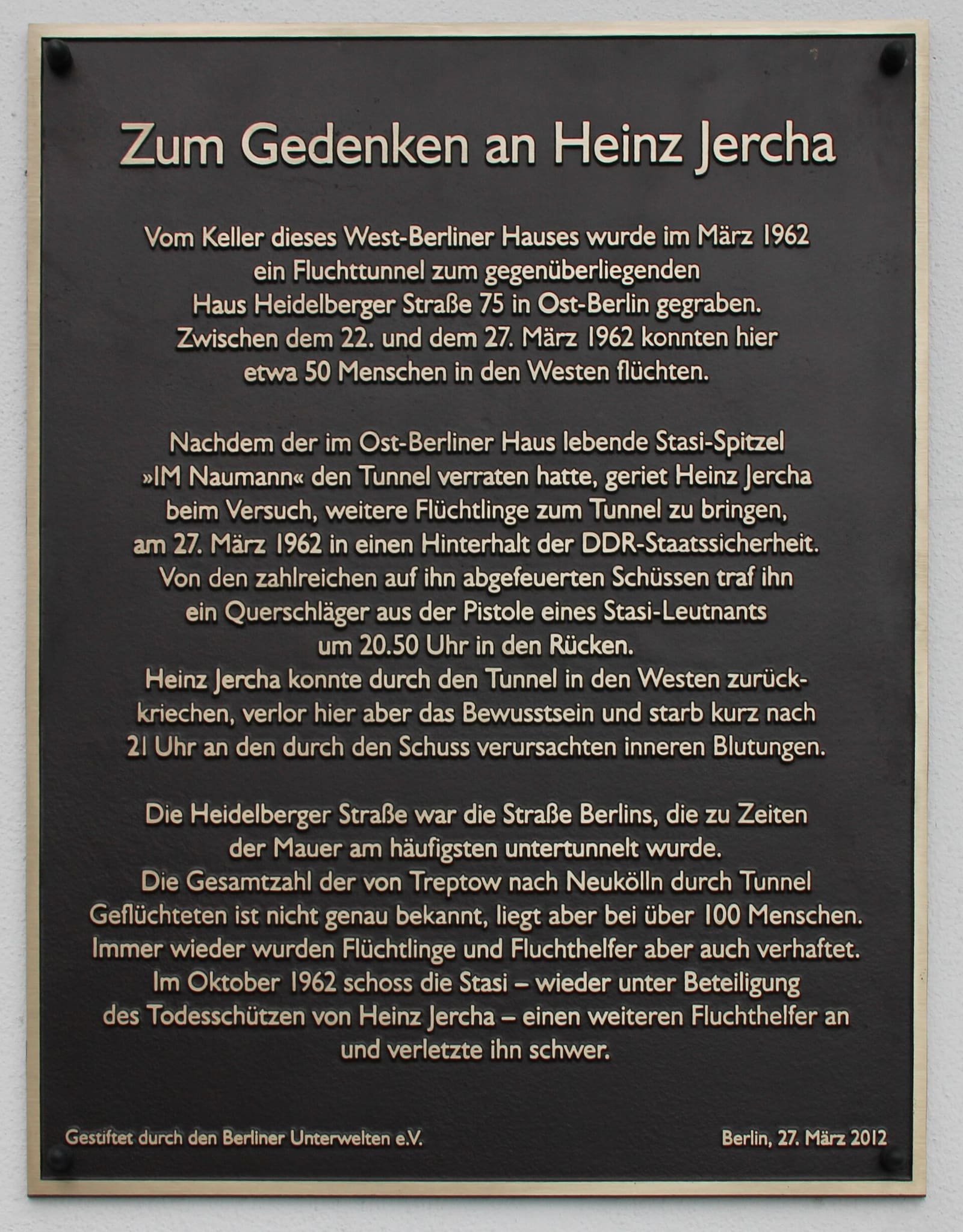Dark bronze plaque on a pale wall headed 'Zum Gedenken an Heinz Jercha' with several paragraphs of German text.