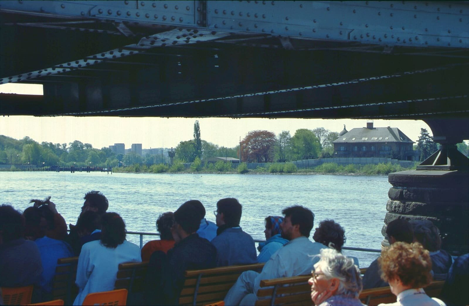 A steel bridge over a wide river, with a wall and a watchtower on the opposite shore.