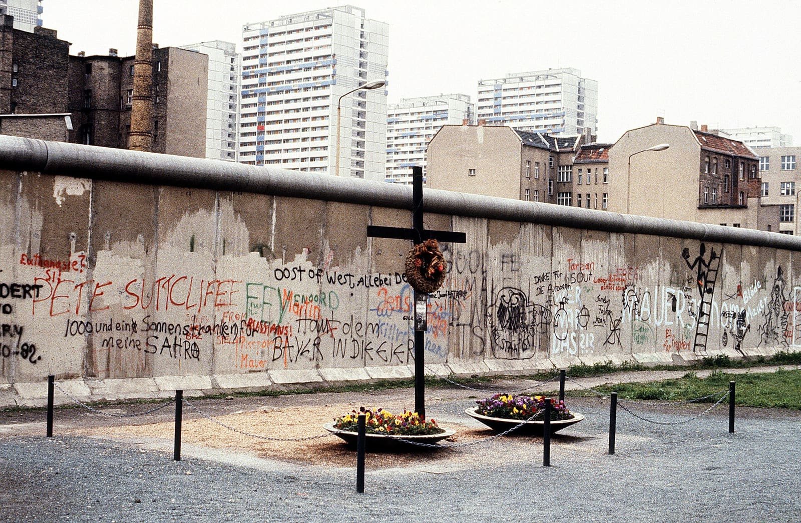 A memorial in front of the grey Berlin Wall on a West Berlin street, 1984