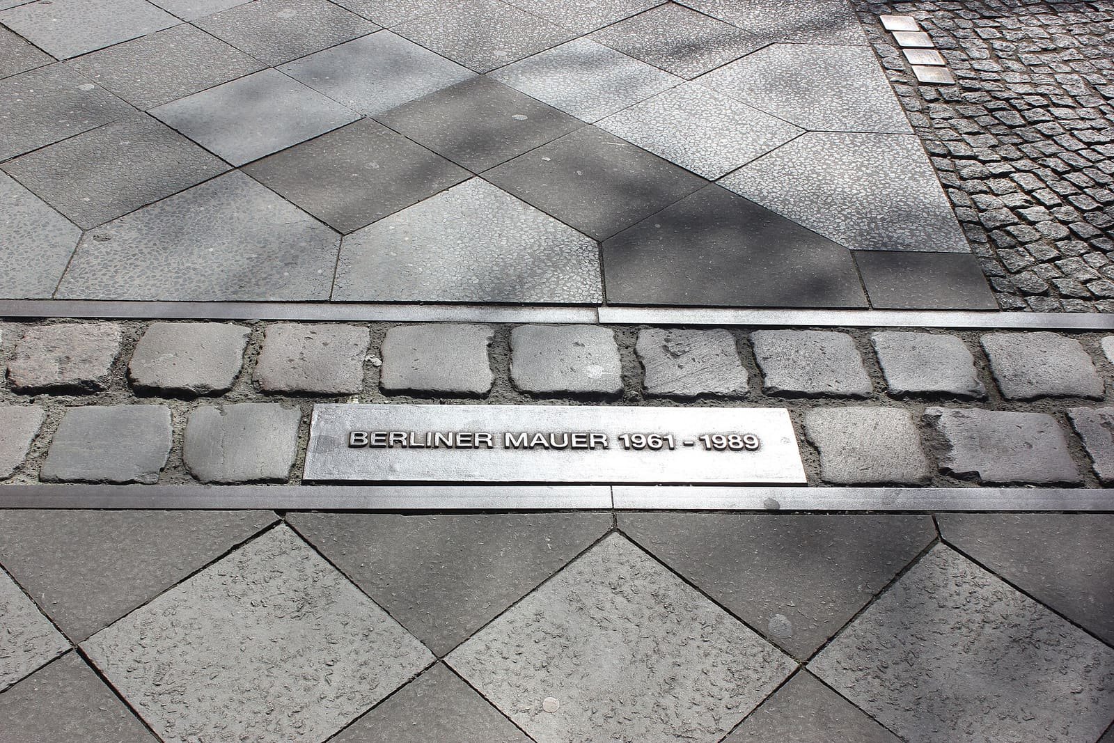 A street with a double line of cobblestones set into the road where the Wall once ran
