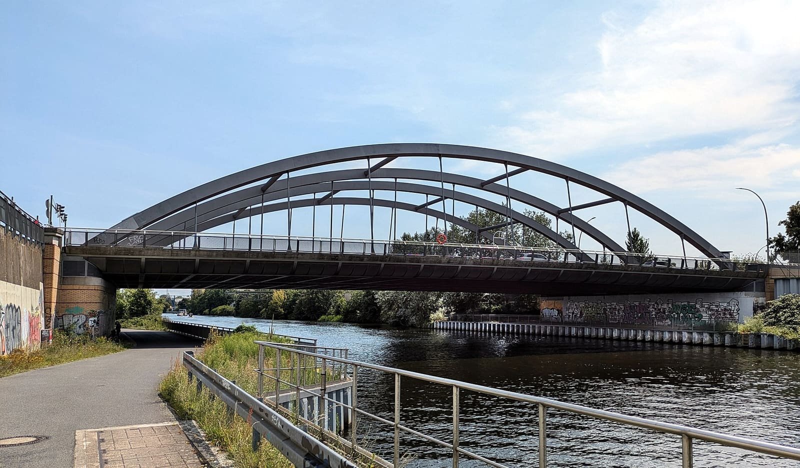 A road bridge crossing a broad canal, with trees along the banks