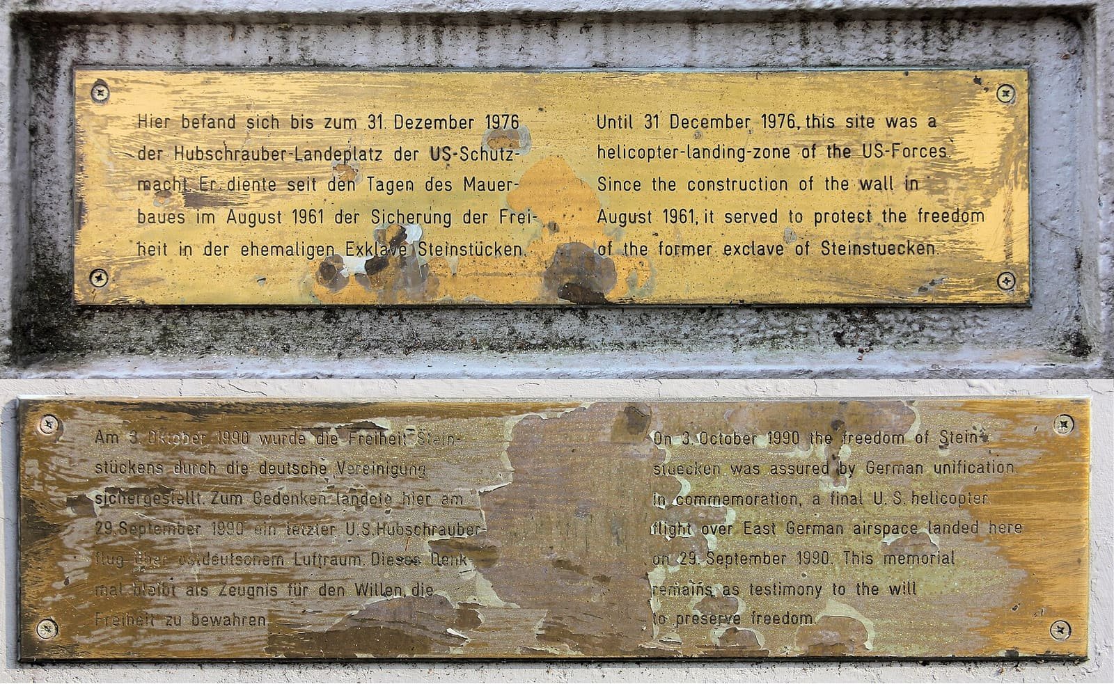 Two weathered brass plaques with German and English text about the US helicopter landing zone in the former exclave of Steinstücken.