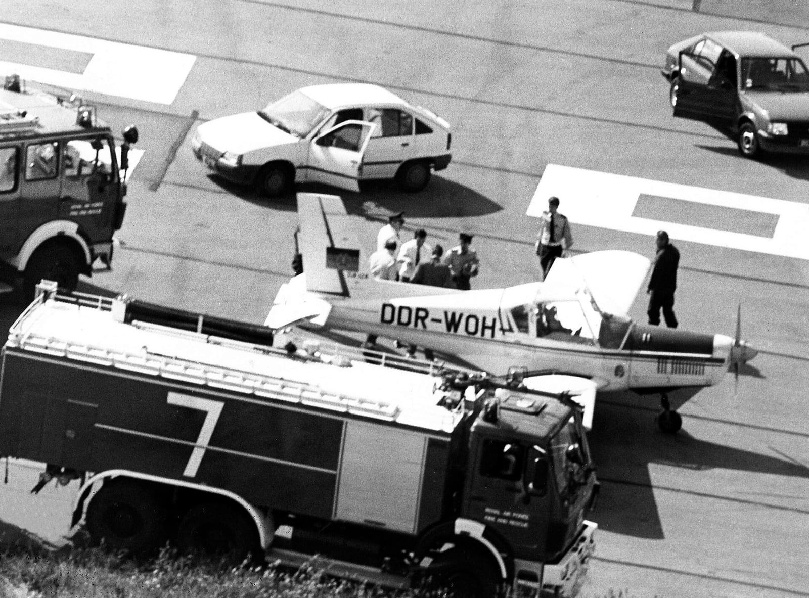 A small single-engine propeller aircraft with East German registration markings standing on an airfield.