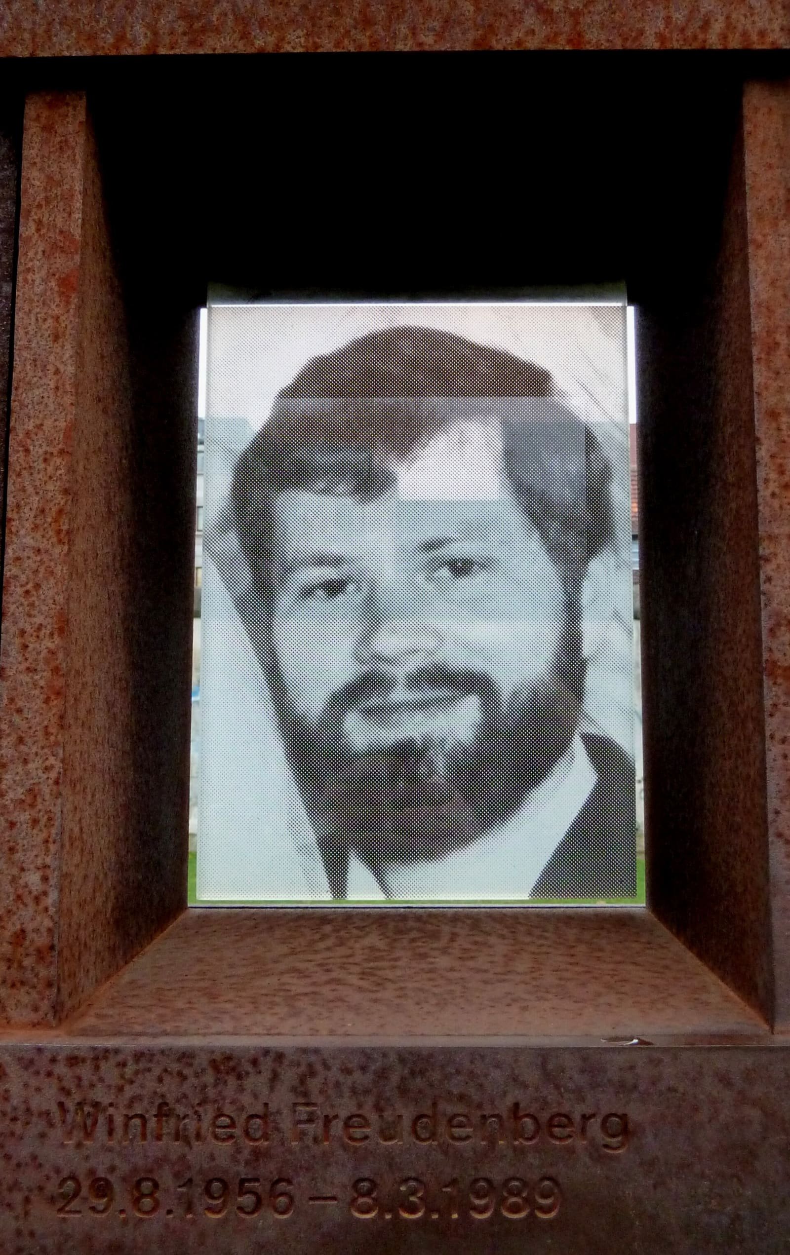 A portrait photograph of Winfried Freudenberg set into a rust-coloured memorial wall.