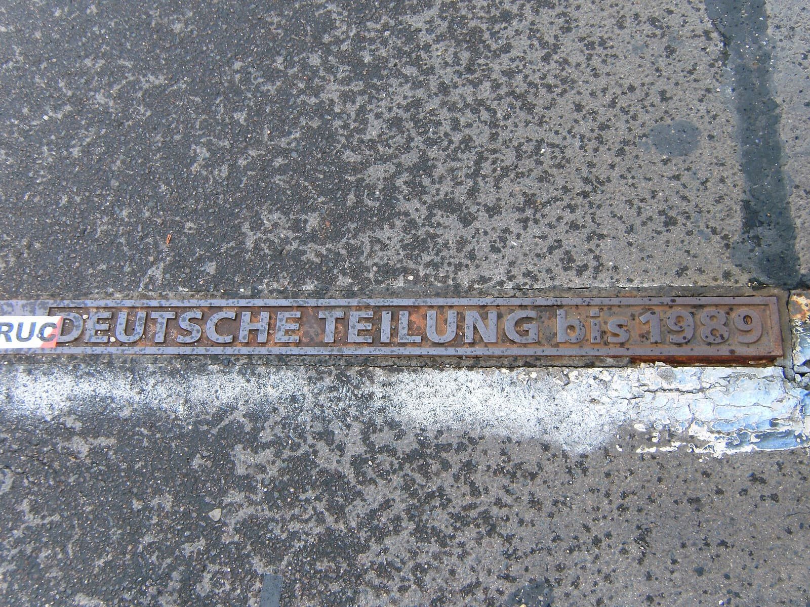 A metal strip set into the bridge's pavement inscribed 'Deutsche Teilung bis 1989'.